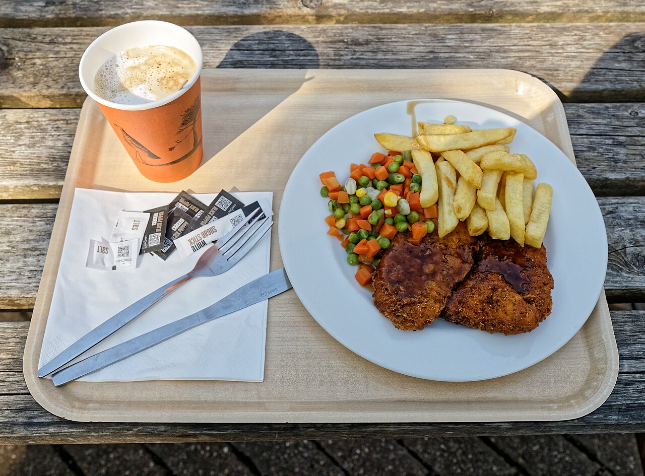An alfresco brunch with chicken escalope, vegetables, chips and coffee on a café patio