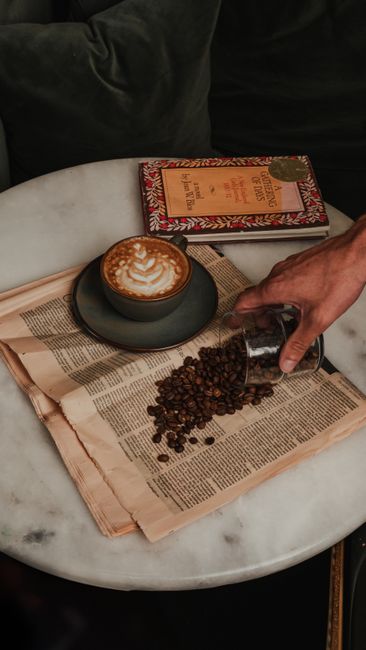 Taza de capuchino con granos de café sobre mesa de mármol
