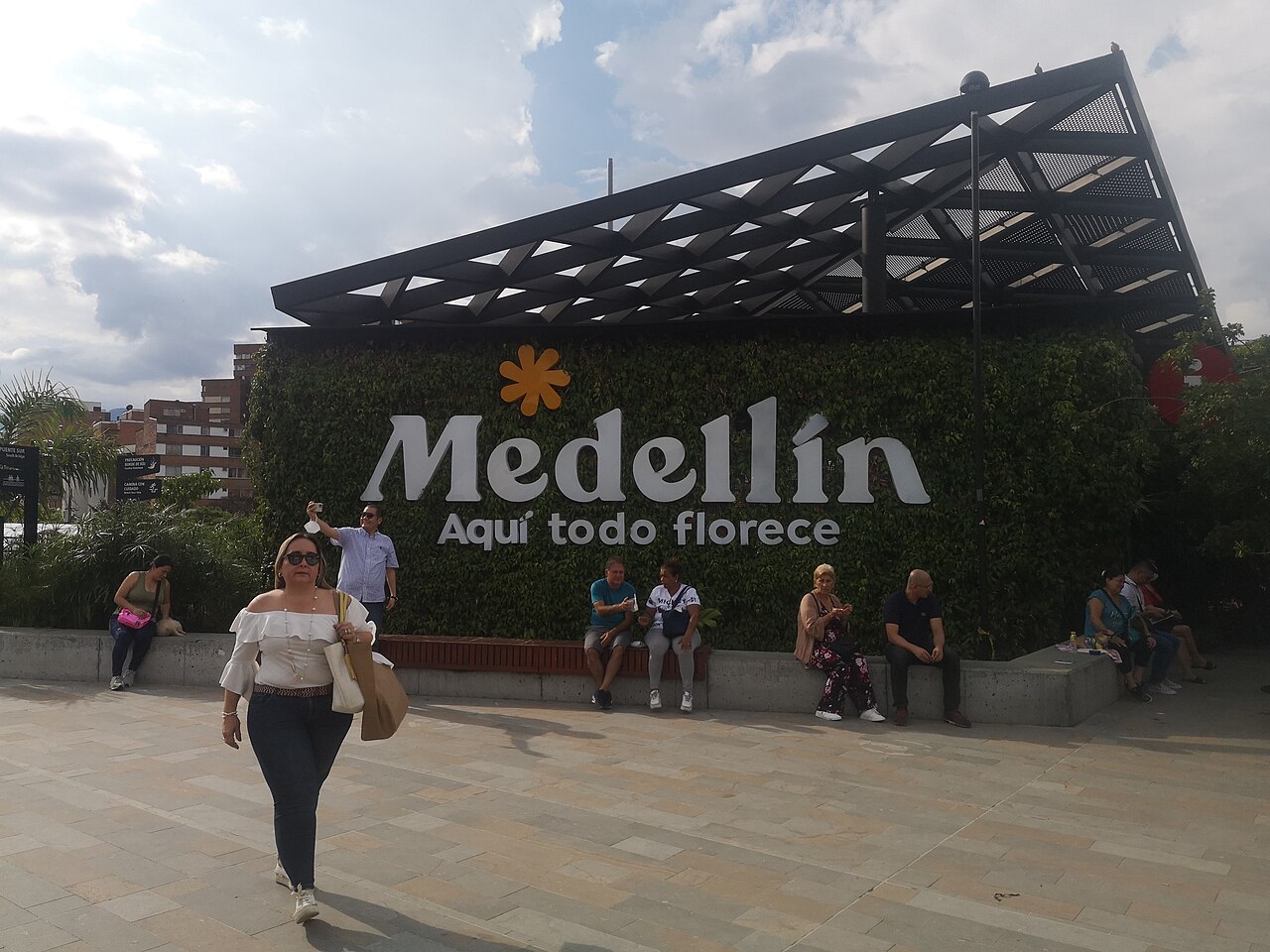 Visitors resting in front of the Medellín Aquí todo florece sign at Parques del Río Medellín in 2022
