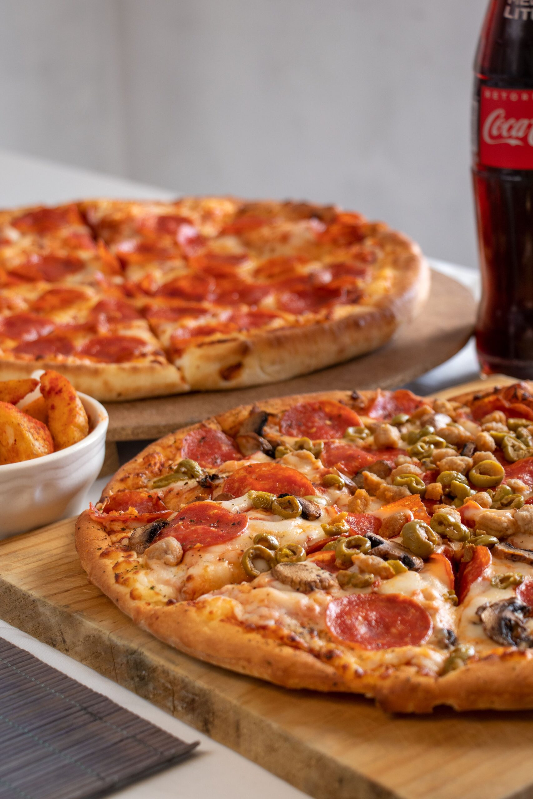 Pizzas de pepperoni y vegetales servidas con refresco