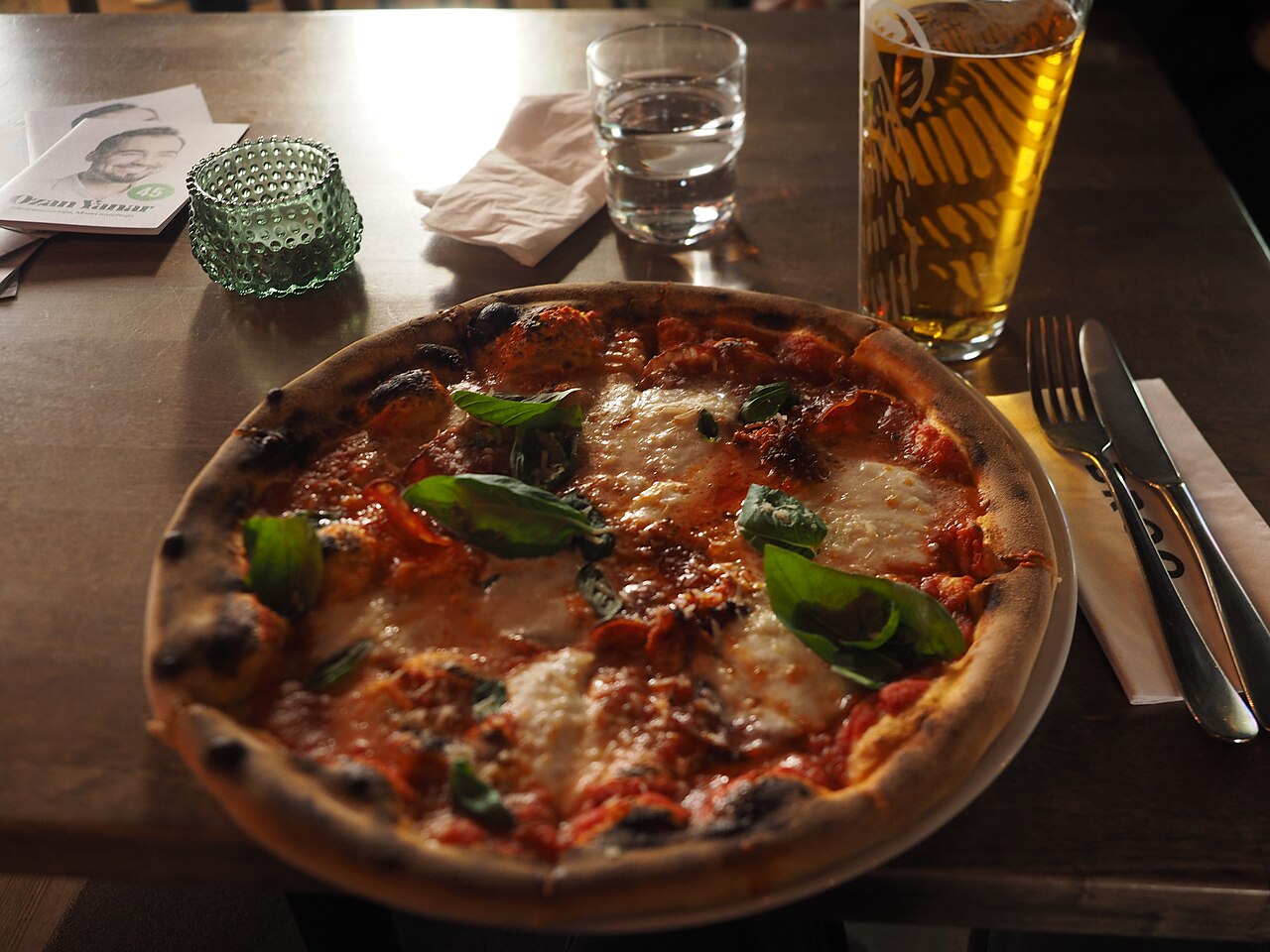 Pizza and a glass of beer served at a restaurant table