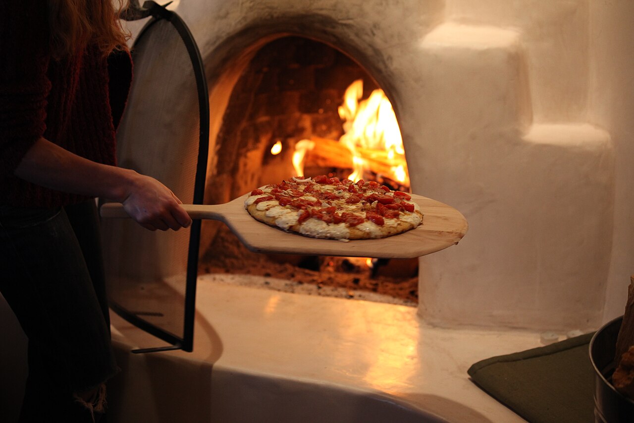 Pizza being placed into a wood-fired oven